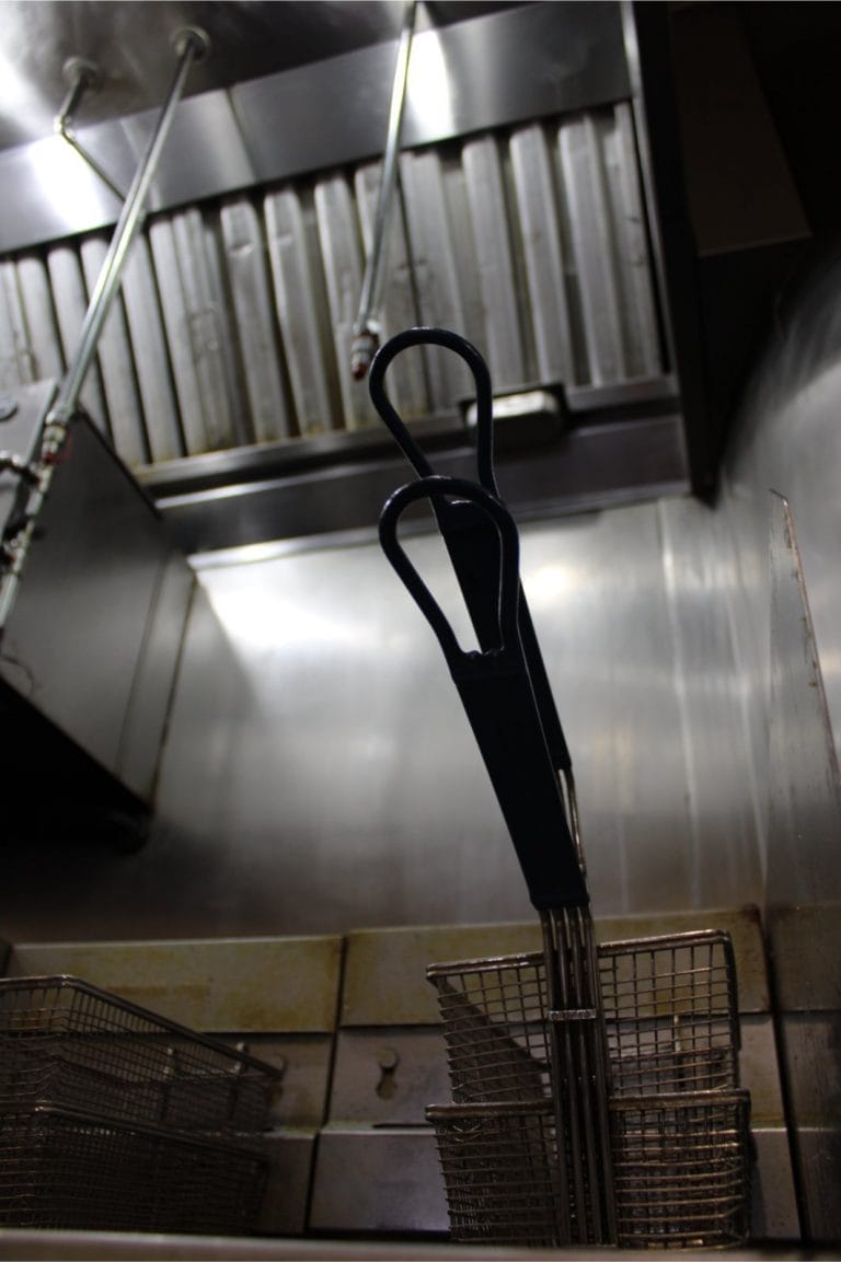 a commercial kitchen deep fryer and vent hood