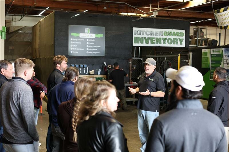 People gathered in a warehouse, focused on discussing the process of ownership steps.